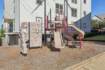 A playground with a slide, rock climber, and monkey bars.